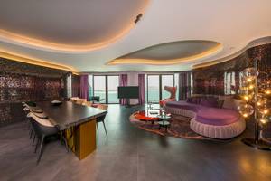 Innenraum des W Dubai - The Palm Hotels mit Esstisch, Couch und Fernseher.