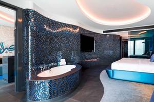 Das Badezimmer der Suite im W Dubai - The Palm mit blauen Fliesen und einer Badewanne.