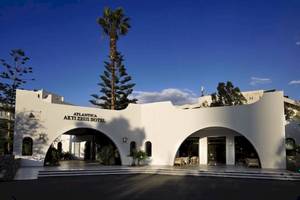 Vorderansicht des Atlantica Akti Zeus Hotels mit zwei bogenförmigen Eingängen und Palmen im Hintergrund.
