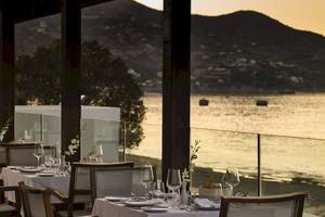 Restaurant mit Meerblick im Atlantica Akti Zeus Hotel, Tische und Stühle sind draußen aufgestellt.