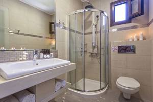 Badezimmer mit Dusche, Toilette, Waschbecken und Kerzen.