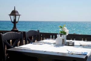 Tisch mit Meerblick im Riviera Beach Hotel, gedeckt mit Tischdecke, Besteck und Blumen.