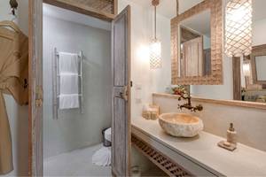 Badezimmer im Eden Beach Khao Lak Resort & Spa mit einer offenen Tür, einem Waschbecken und einem Spiegel.