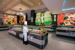 Buffet im Restaurant des Riu Palace Las Americas mit einem Koch, der Essen serviert.