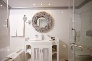 Badezimmer im Mitsis Alila Resort & Spa mit Badewanne, Waschbecken und Dusche.
