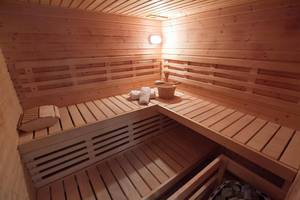 Innenansicht der Sauna im Peninsula Resort & Spa mit Holzbänken, Handtüchern und einem Holzeimer.