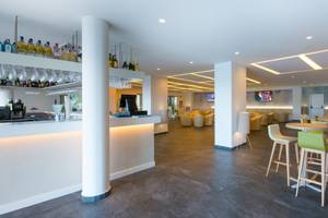 Innenansicht der Bar im Iberostar Selection Lanzarote Park Hotel mit gepolsterten Stühlen und Tischen, einer Theke und Fernsehern an der Wand.