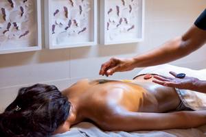 Eine Frau erhält eine Massage mit Steinen im GF Gran Costa Adeje Hotel.