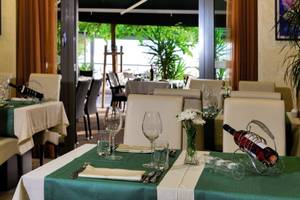 Restauranttisch des Saudade Hotels mit grünem Tischtuch und Weinflaschen.