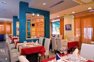 Innenansicht des Restaurants im Saudade Hotel mit blauen und gelben Wänden, weißen Stühlen und rot-weißen Tischdecken.
