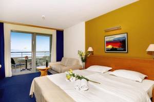 Doppelzimmer im Saudade Hotel mit Balkon und Meerblick, inklusive Bett, Couch, Tisch, und Kunstwerk.
