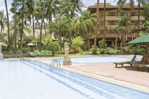 Außenpool des Prama Sanur Beach Bali Hotels mit Sonnenliegen und grünen Sonnenschirmen.