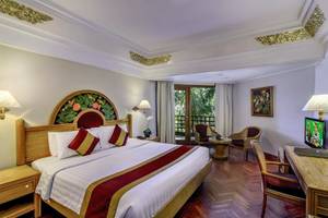 Innenansicht eines Hotelzimmers im Prama Sanur Beach Bali, mit Bett, Schreibtisch und Fernseher.