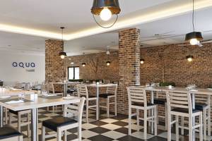 Innenansicht des Aqua Restaurants im Melia Dunas Beach Resort & Spa mit gemustertem Boden und Ziegelwänden.