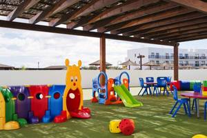 Kinderspielplatz im Melia Dunas Beach Resort & Spa mit bunten Spielgeräten und einem grünen Spielbereich.