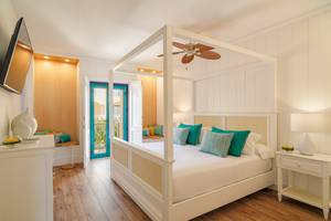 Schlafzimmer im H10 Playa Esmeralda Hotel mit einem Himmelbett, weißem Bettzeug und grünen Kissen.