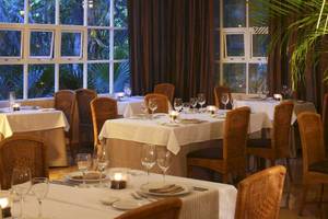 Innenansicht des Restaurants im Catalonia Royal Tulum Hotel mit gedeckten Tischen und Blick auf den Garten