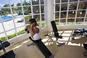 Fitnessstudio im Hotel Catalonia Royal Tulum mit Blick auf den Pool.