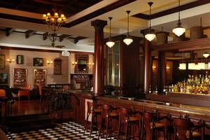 Innenansicht der Bar im Park Rotana Abu Dhabi Hotel mit Holzboden, Barhockern und einer Bartheke mit Flaschen.