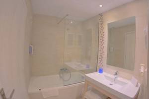 Badezimmer im Elea Beach Hotel mit Badewanne, Dusche, Waschbecken und Spiegel.
