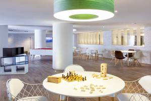 Spielzimmer des Tigotan Lovers & Friends Hotel mit Tischspielen, Sofas und weißer Inneneinrichtung.