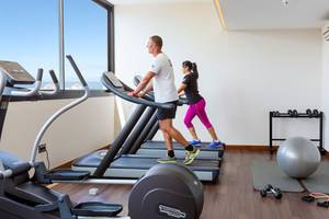 Zwei Personen laufen auf dem Laufband im Fitnessstudio des Tigotan Lovers & Friends Hotels.