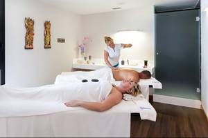 Spa-Behandlung im Hotel Tigotan Lovers & Friends, wo zwei Personen eine Massage auf dem Bett genießen.