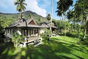 Außenansicht des Hilton Seychelles Labriz Resort & Spa mit zwei Chalets, umgeben von Palmen und grüner Landschaft.