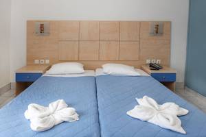 Doppelbett im Hotelzimmer Eurovillage Achilleas mit zwei Kissen und weißen Handtüchern