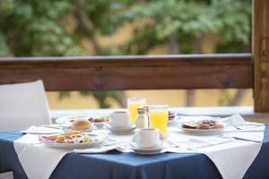 Frühstückstisch im Eurovillage Achilleas Hotel mit Speisen, Getränken und Geschirr.