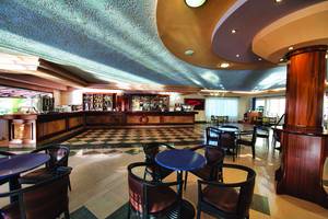 Innenbereich der Rezeption des Eurovillage Achilleas Hotels mit gemustertem Boden und runden Tischen.