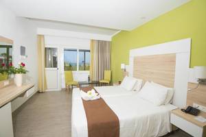 Eurovillage Achilleas Hotelzimmer mit zwei Betten, grünen Wänden und einem Blick auf das Meer.