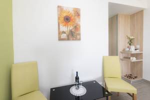 Innenansicht des Eurovillage Achilleas Hotels mit gelben Stühlen, schwarzem Tisch und Sonnenblumen-Kunstwerk an der Wand.