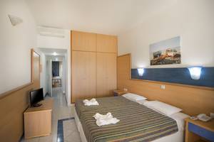 Innenansicht eines Hotelzimmers im Eurovillage Achilleas mit zwei Betten, Fernseher, Kleiderschrank und Deko.