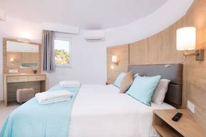 Schlafzimmer im Eurovillage Achilleas Hotel mit zwei Betten, Holzwand, Klimaanlage und Bettwäsche.