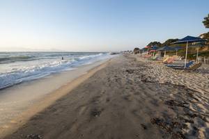 Strand mit Sonnenschirmen und Strandliegen am Meer bei Sonnenuntergang