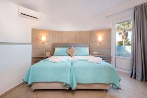 Doppelbett-Zimmer im Eurovillage Achilleas Hotel mit blauen Laken und Kissen.