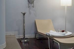 Relaxationsbereich im Hotel Ku Damm 101 mit Liege, Tisch und Leuchte.