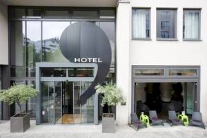 Eingang des Ku Damm 101 Hotels mit Glasfassade und schwarzen Elementen.