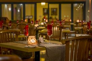 Restauranttisch im Le Peninsula Bay Beach Resort mit rotem Weinglas und Kerze.