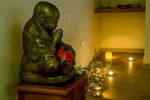 Buddha-Statue im Le Peninsula Bay Beach Resort & Spa mit roten und weißen Blumen.