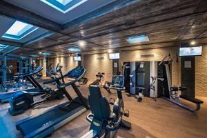 Innenansicht des Fitnessstudios des Corissia Princess Hotels mit verschiedenen Geräten und Monitoren.