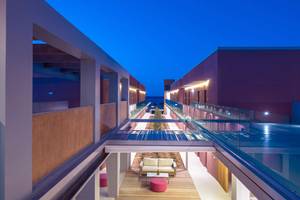 Innenbereich des Corissia Princess Hotels bei Nacht mit einer Glasbrücke und Möbeln.