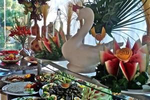 Ein Buffettisch mit einer Vielzahl von Früchten und Blumen als Dekoration, einschließlich Wassermelonen, Rosen und anderen Blumen, in einem Hotel.