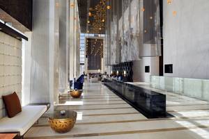 Lobby des Southern Sun Abu Dhabi Hotels mit Marmorboden, Sitzecken und orangefarbenen Pendelleuchten.