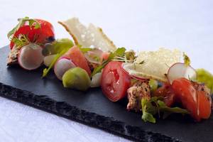 Ein Gericht im Southern Sun Abu Dhabi mit Tomaten, Radieschen und grünem Gemüse auf einem schwarzen Teller.
