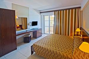 Innenansicht eines Hotelzimmers im Akti Beach Club mit Bett, Schreibtisch und Fernseher.