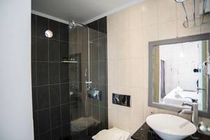 Badezimmer im Beach Boutique Hotel mit Duschkabine, Waschbecken und Spiegel.