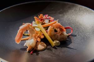 Garniertes Shrimps-Gericht auf einem schwarzen Teller serviert.