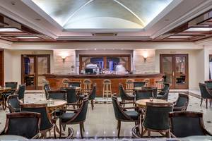 Innenansicht der Bar im Mitsis Grand Hotel Beach mit Theke und Sitzgelegenheiten.